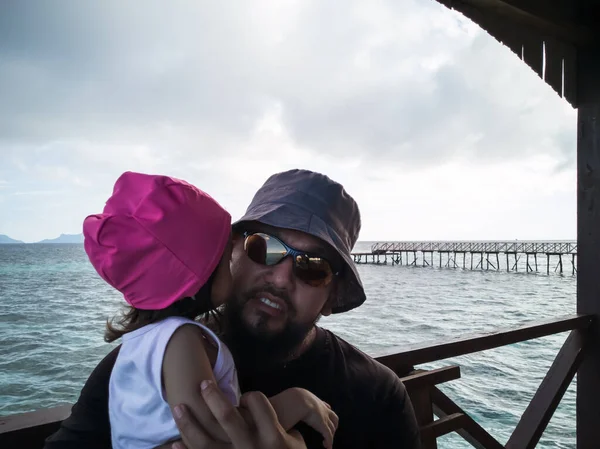 Lüks tatil köyü, mutlu aile rahatlaması. Babam ve yeni yürümeye başlayan çocuk su dağ evi tatil köyünün güvertesinde oturuyor. Yaz tatili fikri.