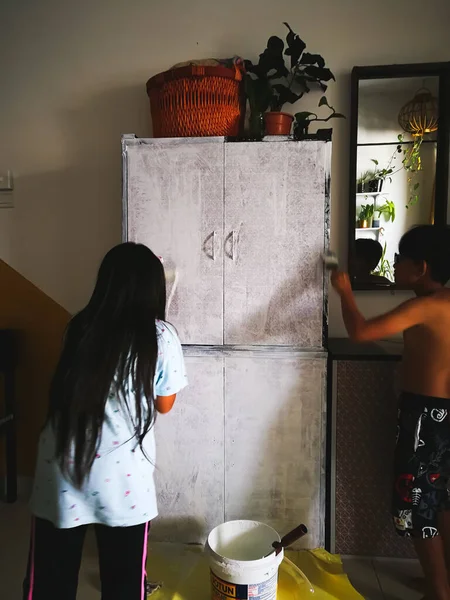 マレーシアのSelangor 12月2019 若い子供たちは 白い色の塗料で木製の寝室のクローゼットをペイントブラシを持っています 子供の家具の改修と復元を学ぶ 自宅で子供たちと一緒にプロジェクトを行う — ストック写真