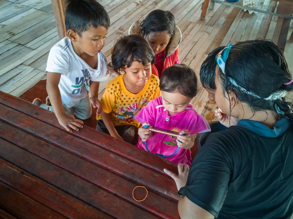 Semporna, Malezya - 26 Kasım 2019: Çocuklar cep telefonunda video izliyorlar. Teknoloji kullanan çocuklar.