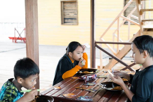 Semporna, Malezya - 25 Kasım 2019: Çocuklar açık havada kahvaltı yaparlar.