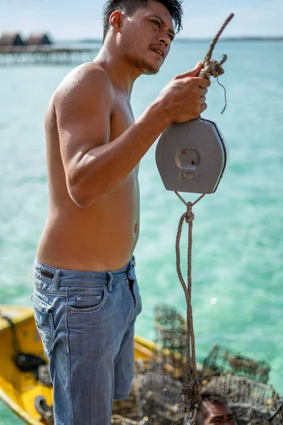 Semporna, Malezya - 26 Kasım 2019: Yerel adam Bum Bum Adası 'ndaki balıkçıdan satın alırken balık ağırlığı tartısını tutuyor.