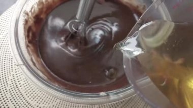 Çikolatalı kek hamuru ya da hamuru su dökerken bir el mikseriyle karıştırmak. Yemek hazırlama. Yakın görünüm.