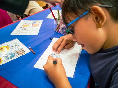 Kuala Lumpur, Malezya - Kasım 2019: Geri dönüşümlü plastik bir konteynır örtüsüne çizim yapan genç bir çocuğun yüksek açılı yakın çekimi. Anahtarlık yapıyorum..