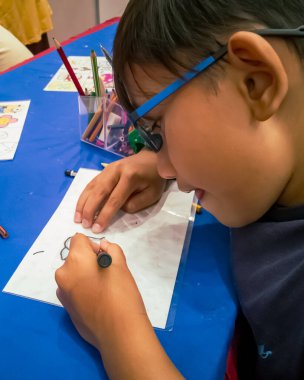 Kuala Lumpur, Malezya - Kasım 2019: Geri dönüşümlü plastik bir konteynır örtüsüne çizim yapan genç bir çocuğun yüksek açılı yakın çekimi. Anahtarlık yapıyorum..