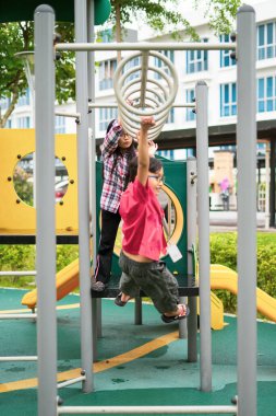 Genç Asyalı çocuklar maymun tezgahına asılıyor. Mahalledeki oyun parkında egzersiz yapmak için..