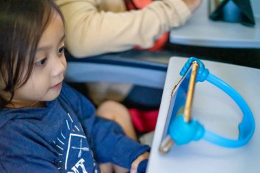 Küçük çocuk uçağın içinde tablet kullanarak rahatlıyor..