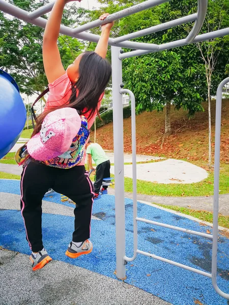 Oyun parkındaki maymun barında asılı duran aktif genç kızın bulanık fotoğrafı.