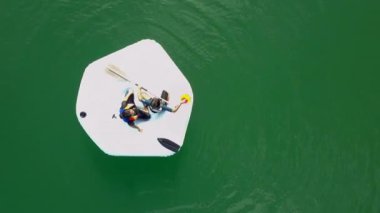 Hava kamerası yukarı çıkıyor. Heyecanlı çocuklar can yelekleri giyip Kenyir Gölü, Malezya 'da şişme bir teknenin keyfini çıkarıyorlar..
