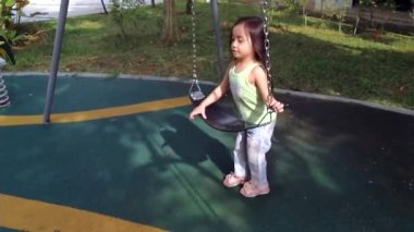 Küçük kız salıncakla eğleniyor. Parlak ve güneşli bir sabahta salıncakta oynayan küçük kız..