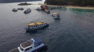 Redang, Malezya - 2018 dolaylarında: Terengganu bayraklarıyla adanın iskelesinden hareket eden tur teknelerinin havadan görünüşü.