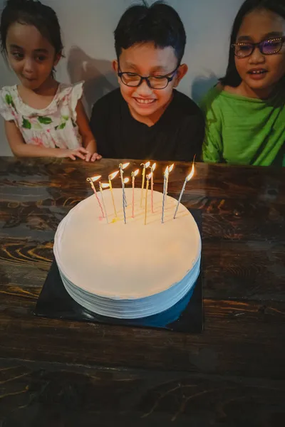 白いケーキの上にカラフルなキャンドル 一緒に誕生日を祝う子供たち — ストック写真