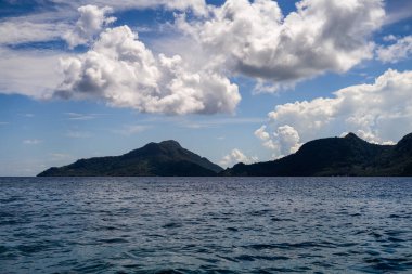 Kutlamalar deniz yüzeyi yaz dalgaları arka planı. Ufukta bulutlu ve adalı egzotik su manzarası. Doğal tropik su cenneti. Semporna doğa rahatla. Tropikal ada tatil beldesi. Okyanus doğası sükuneti.