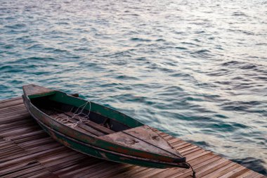 İskelede duran eski ahşap tekne güzel Semporna turkuaz denizine bakıyor..