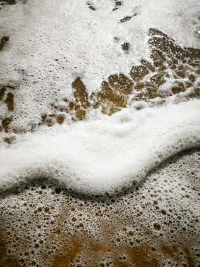 Kumsalda kumlu kumsalda beyaz bir köpük 