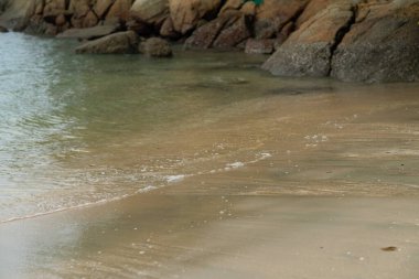 Kumsalın arka planında köpüklü yumuşak dalgalar.