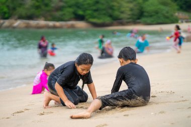 Genç Asyalı çocuklar sahilde oynuyorlar. Tatil ve rahatlama kavramı.