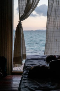 Deniz manzaralı arka plan, çocuklar yatağın üzerinde uyur ve suya bakar..