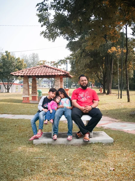 公園のベンチに幸せな家族が座っている — ストック写真