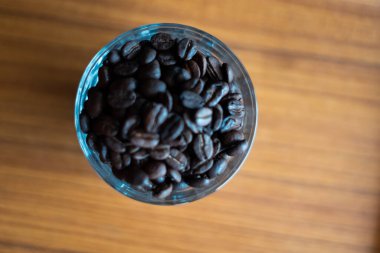 Bardaktaki kahve çekirdekleri ahşap arka planda..