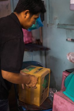 Semporna, Malezya - 28 Kasım 2019: Bir esnaf, uçakla birlikte hediye olarak getirmek isteyen müşteriler için bir kutuda satılan ürünlerini paketliyor.