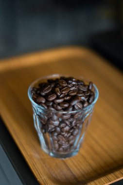 Bardaktaki kahve çekirdekleri ahşap arka planda..