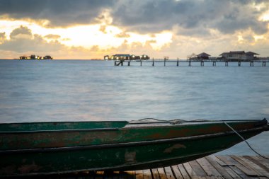 İskelede duran eski ahşap tekne güzel Semporna turkuaz denizine bakıyor..