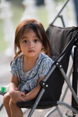 Bebek arabasında oturan sevimli küçük kız kameraya bakıyor..