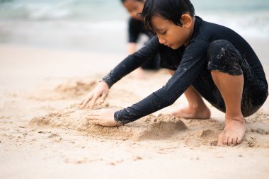 Genç Asyalı çocuklar sahilde oynuyorlar. Tatil ve rahatlama kavramı.