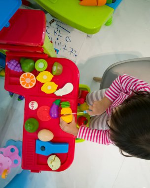 Yeni yürümeye başlayan çocuğun oyuncaklarıyla yemek pişirme görüntüsü..