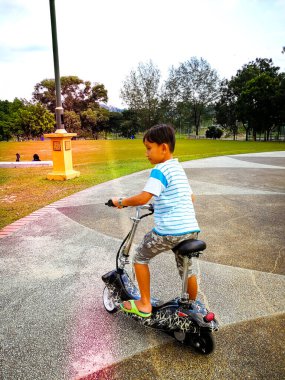 Sokakta scooter süren çocuk.