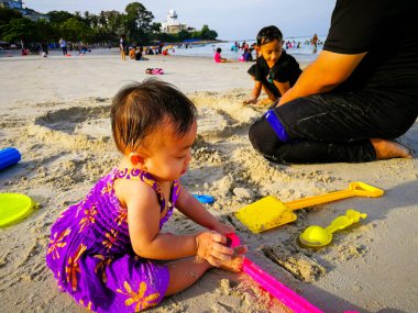Baba ve çocuklar kumsalda oynuyorlar.