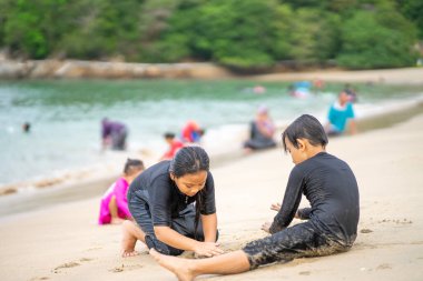 Genç Asyalı çocuklar sahilde oynuyorlar. Tatil ve rahatlama kavramı.
