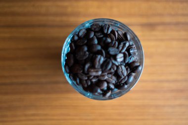 Bardaktaki kahve çekirdekleri ahşap arka planda..