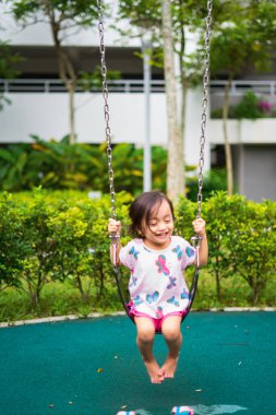 Aktif küçük çocuk oyun alanında salıncak oynuyor. Mutlu ve eğlenceli zaman.