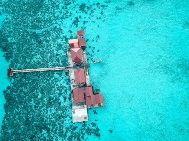 Turkuaz sudaki tropikal bir adanın havadan görünüşü. Tropikal ada beldesindeki su villaları üzerinde lüks.