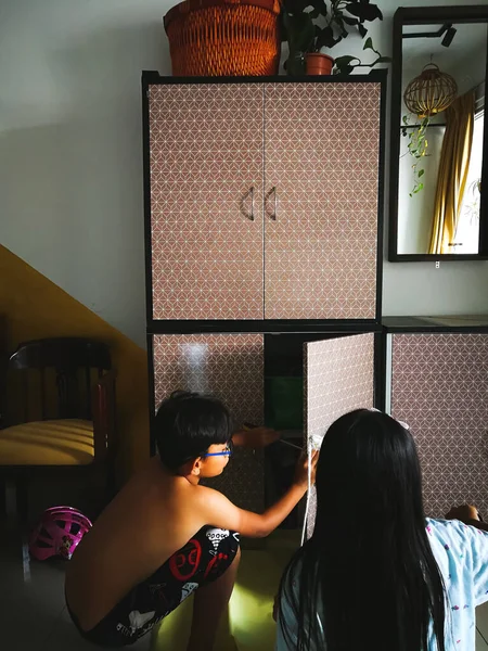 マレーシアのSelangor 12月2019 若い子供たちは 白い色の塗料で木製の寝室のクローゼットをペイントブラシを持っています 子供の家具の改修と復元を学ぶ 自宅で子供たちと一緒にプロジェクトを行う — ストック写真
