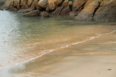 Kumsalın arka planında köpüklü yumuşak dalgalar.