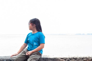 Küçük kız yalnız oturuyor ve denize bakıyor..