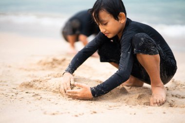 Genç Asyalı çocuklar sahilde oynuyorlar. Tatil ve rahatlama kavramı.