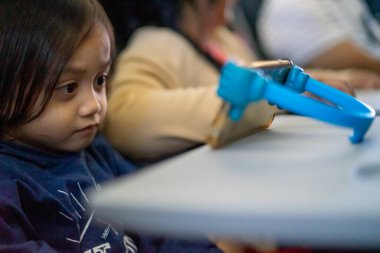 Küçük çocuk uçağın içinde tablet kullanarak rahatlıyor..