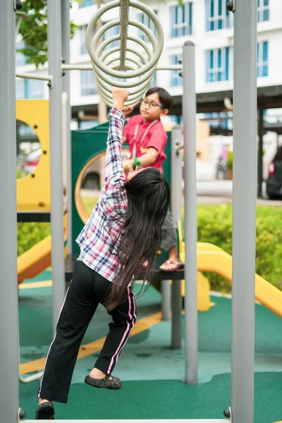 若いアジアの子供たちはサルのバーにかかっている 近所の屋外遊び場で運動するには — ストック写真