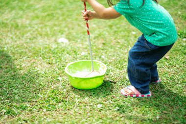 Parkta sabun köpüğüyle oynayan sevimli aktif Asyalı kız.