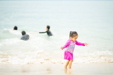 Mutlu Asyalı çocuk sahilde koşuyor.