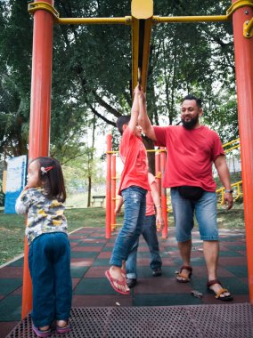 Parktaki maymun parmaklıklarında oynayan Asyalı baba ve çocuklar.. 