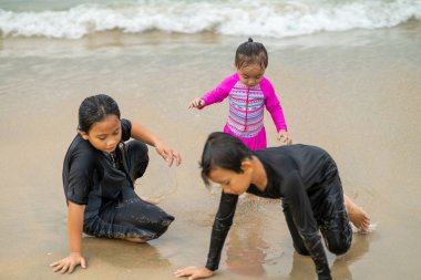 Genç Asyalı çocuklar sahilde oynuyorlar. Tatil ve rahatlama kavramı.