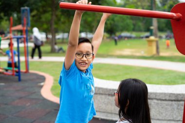 Erkek ve kız kardeş parkta egzersiz makineleriyle çalışıyor.