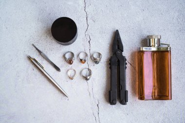 Şık erkek yüzükleri, kalem, aletler, mendil, poz ve tımar için parfüm. Beton arka planda metroseksüel sezaryenler. Şehir kompozisyonu. Üst görünüm.