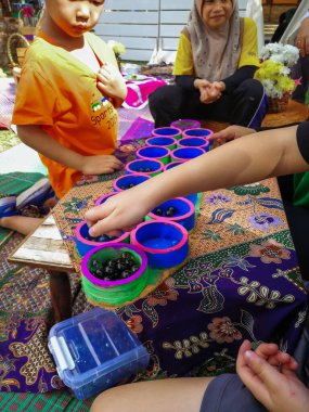 Selangor, Malezya - 8 Aralık 2019: Bangi 'deki Taman Tasik Cempaka' da düzenlenen Majlis Perbandaran Kajang etkinliğinde geri dönüşümlü eşyalarla kongkak oynayan insanlar. Çevreye önem vermek.