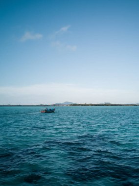 Sürat teknesi dalgalı denizde hızla ilerliyor. Çok güzel bir gün. Arka planda mavi suyun üzerinden geçen hızlı gemi mavi gökyüzünü ve adayı gösteriyor..