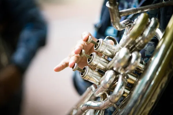 The trumpeter is playing on a silver trumpet. Trumpet player